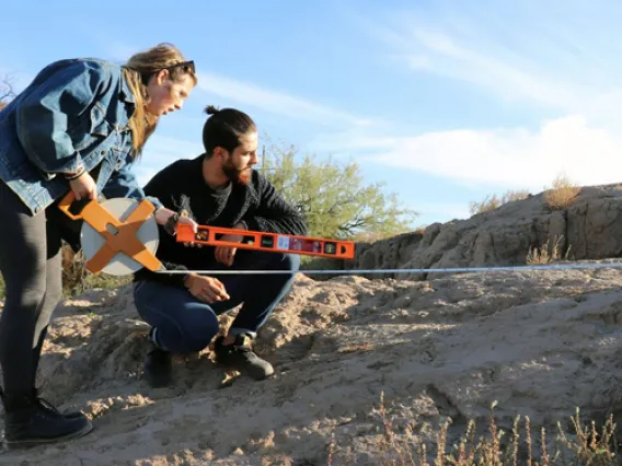 Environmental science students working with geographic measuring tools in the desert.