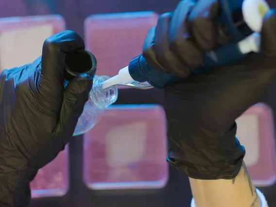 A close up shot of gloved hands working with liquids in a lab.