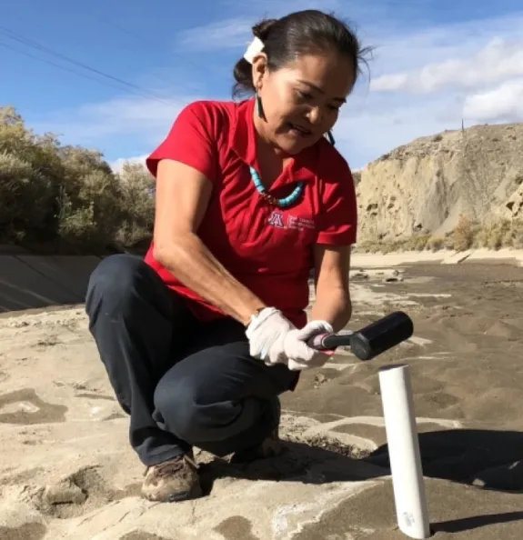 Karletta Chief collects a sediment core sample from a river to measure for contaminants.