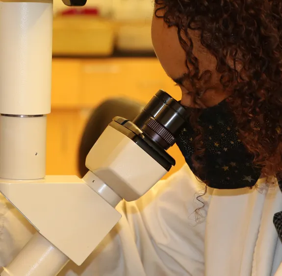 Luisa Ikner looking through a microscope.