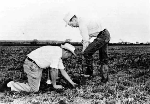 two men sampling soil in a large field